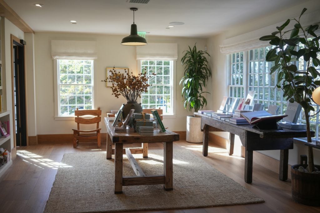 Sunlit book displays on wooden tables inside Godmothers bookstore