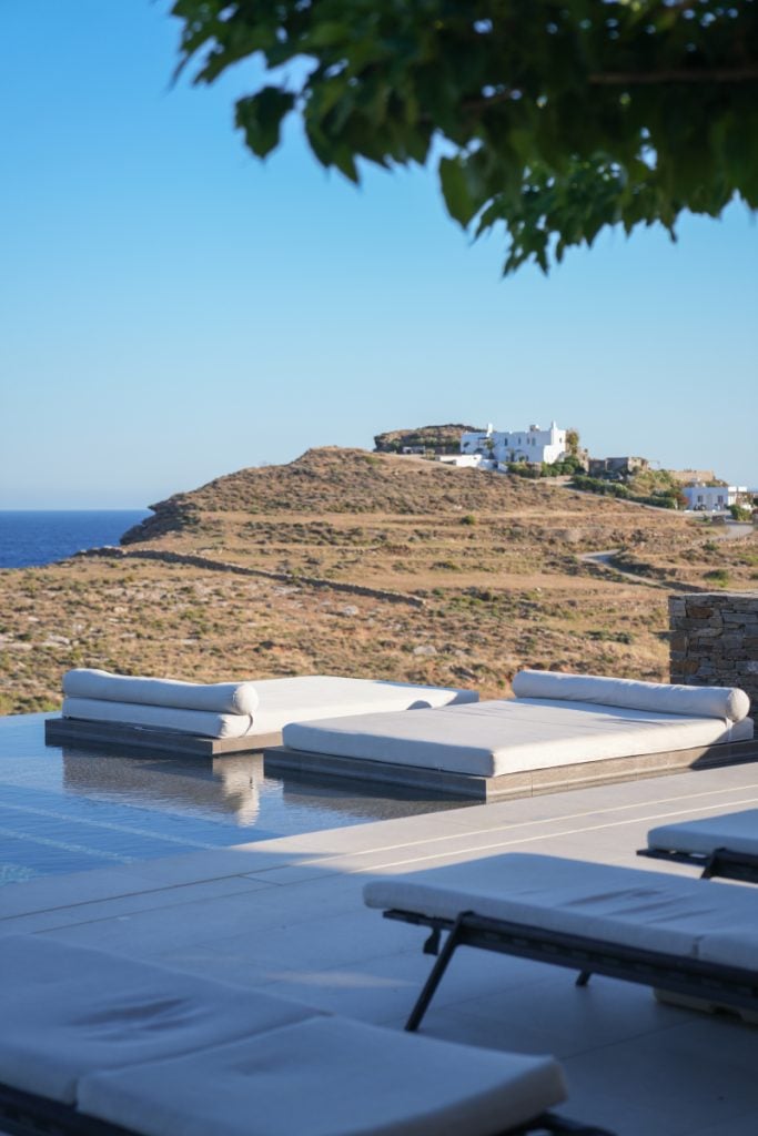 Poolside daybeds at NOS Hotel overlooking the sea and terraced hills.