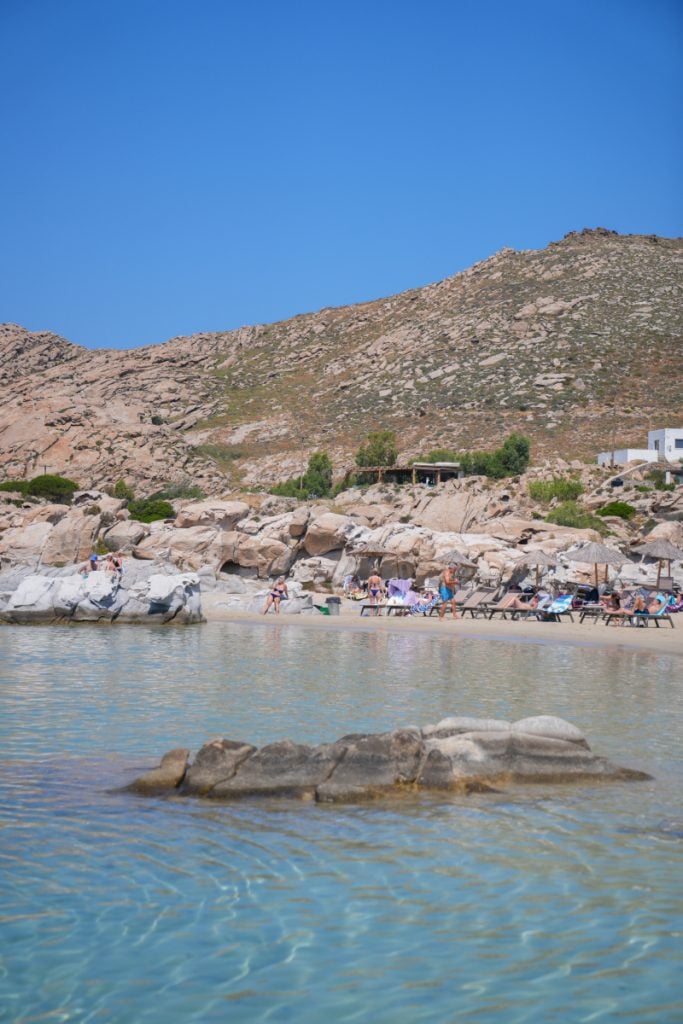 Rocky Paros cove with beach loungers and clear water