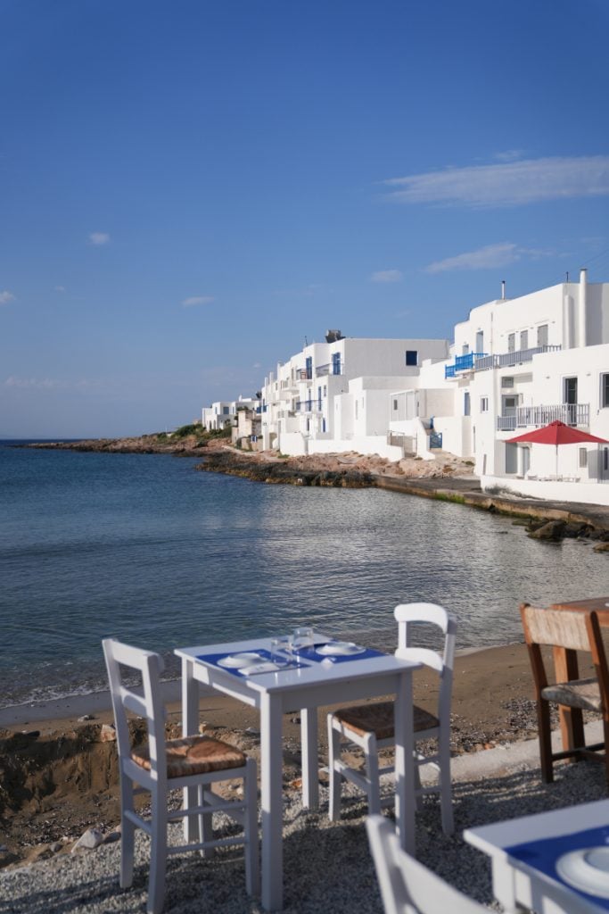 Waterfront dining table beside whitewashed homes in Paros
