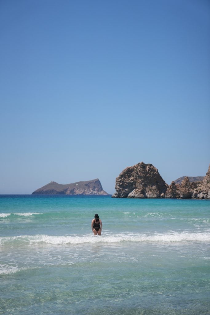 Woman wading into turquoise water at Plathiena Beach