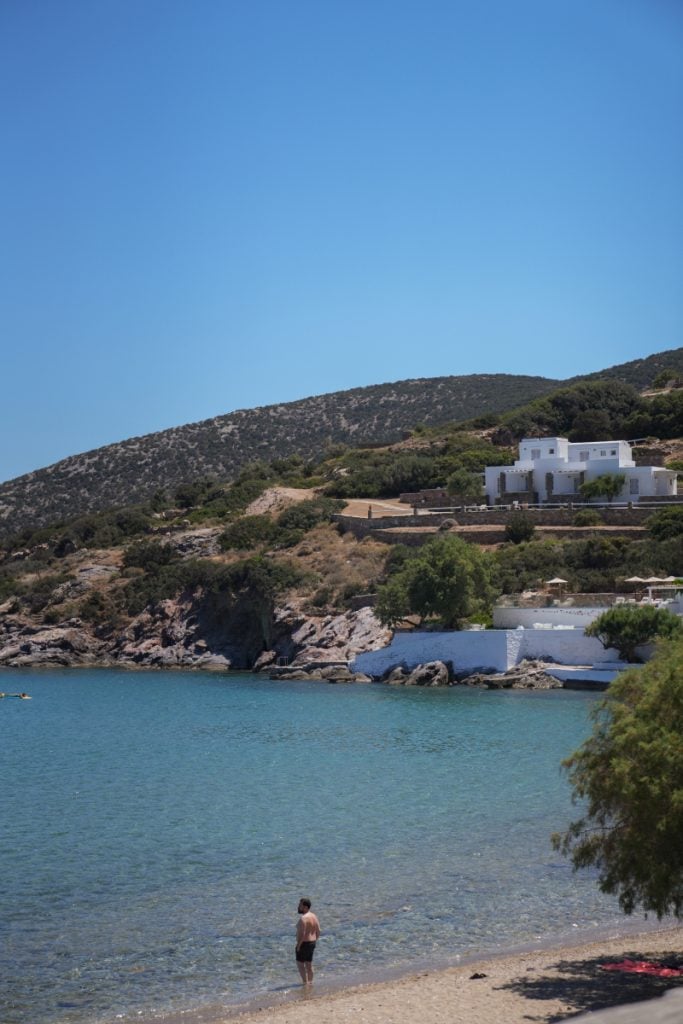 Beach at Platis Gialos with calm blue water and white buildings across the bay.