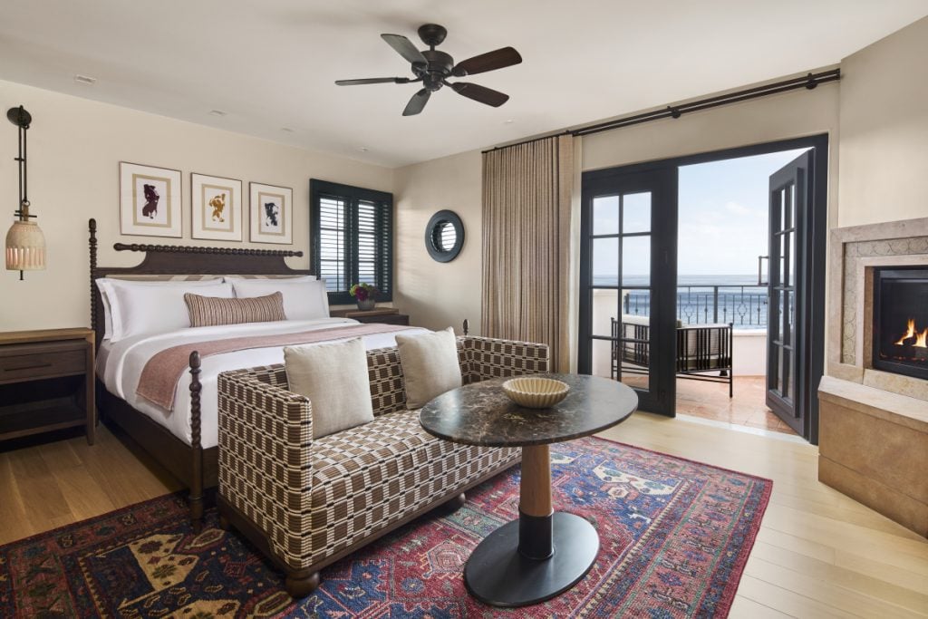 Guest bedroom with a fireplace, sitting area and ocean-view balcony at The Ritz-Carlton Bacara