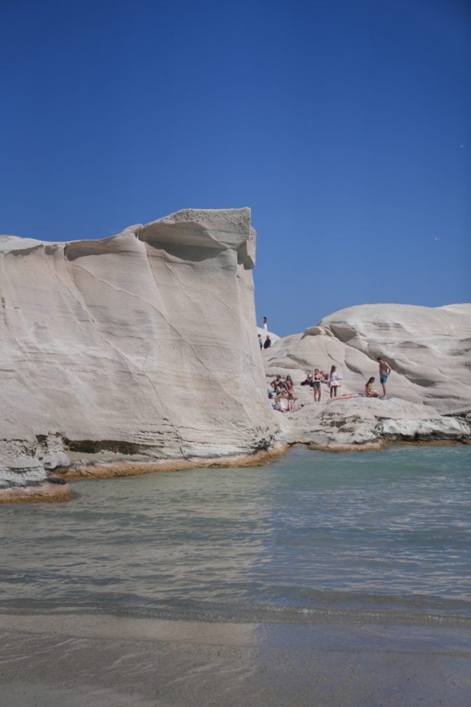 Sunbathers beneath white volcanic cliffs at Sarakiniko
