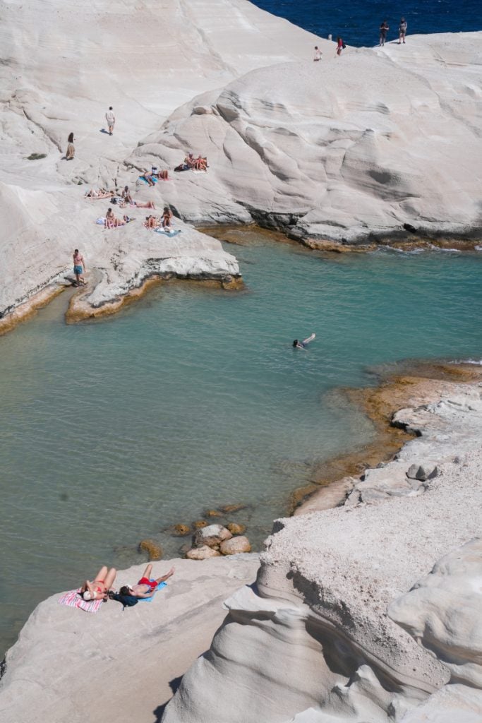 Swimmers and sunbathers among Sarakiniko's white volcanic rocks