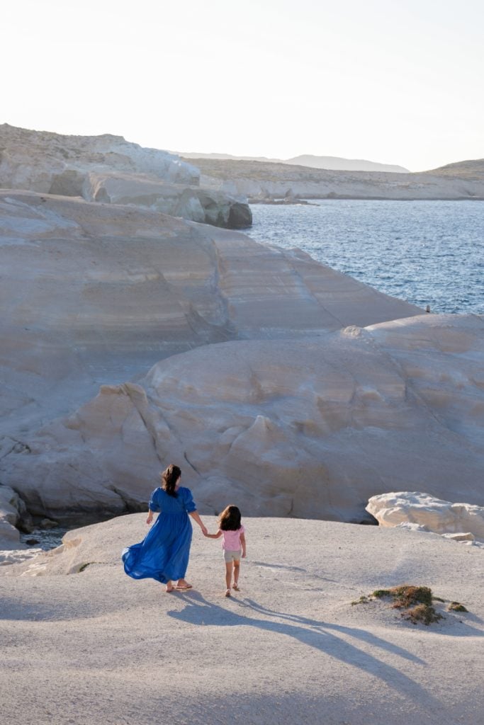 Woman and child walking across Sarakiniko’s white rocks