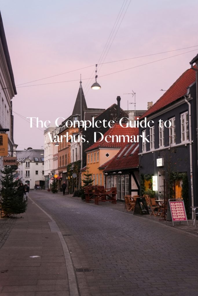 Aarhus travel guide graphic over a cobblestone street at dusk