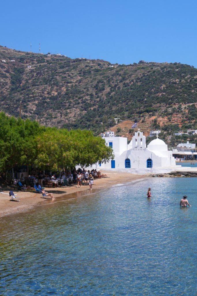 White seaside church and swimmers at Vathi Beach