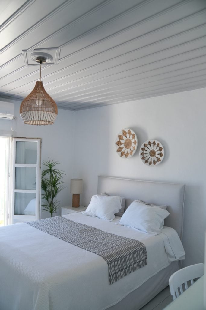 White bedroom at Villa Glaros with woven pendant lighting and decorative wall baskets.