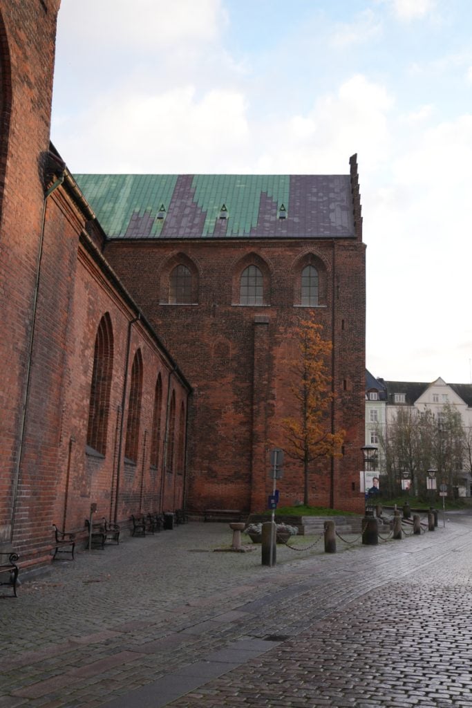 Brick exterior of Aarhus Cathedral beside a cobblestone street