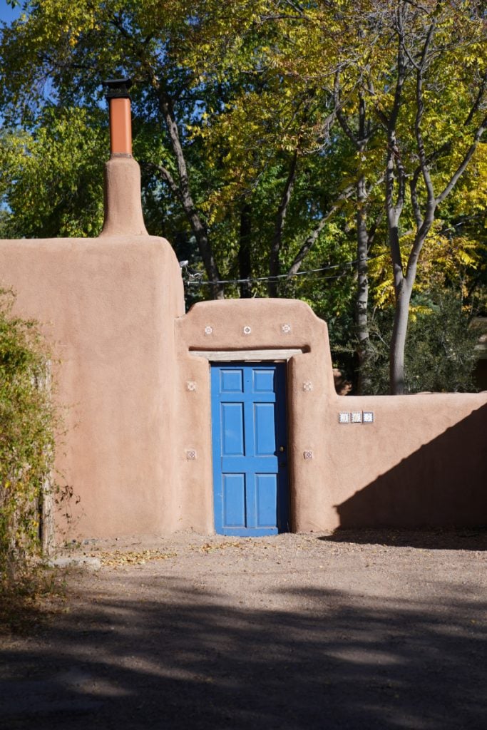 Blue door and chimney in a curved adobe wall