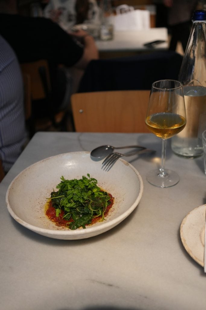 Herb-topped dish and white wine at Akra