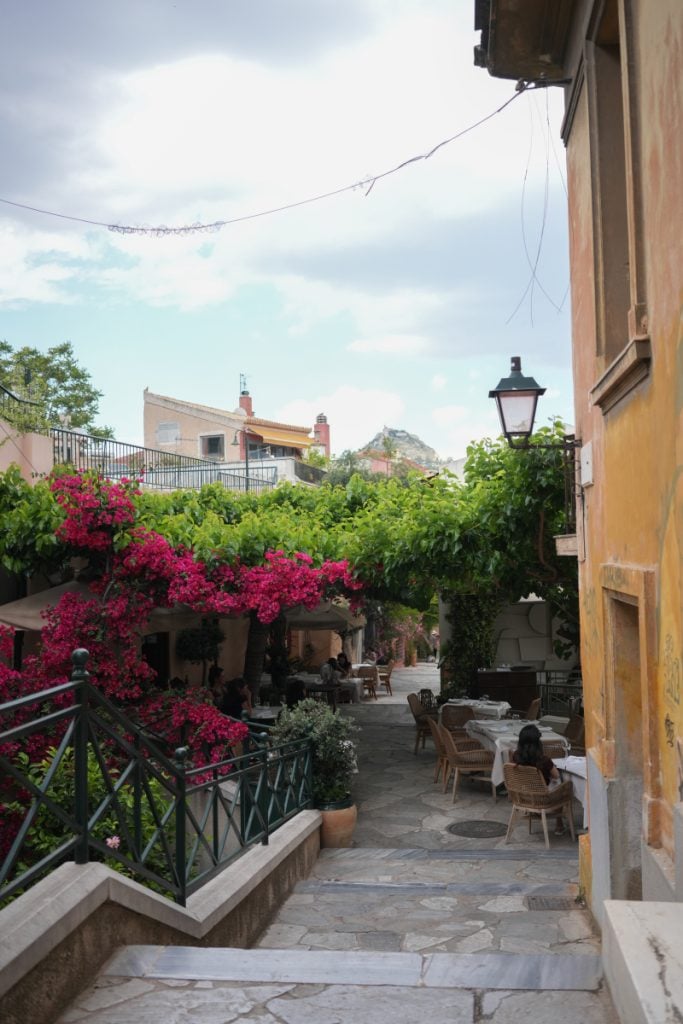Restaurant terraces and bougainvillea along stone steps in Plaka
