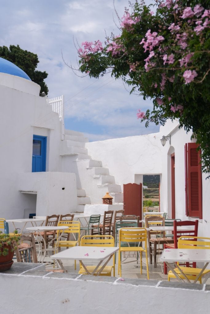 Colorful cafe chairs beneath pink bougainvillea in Artemonas.