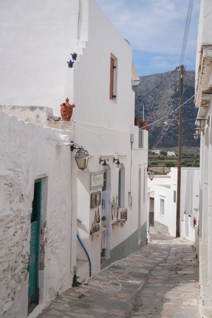 Narrow stone-paved lane between whitewashed buildings in Artemonas.