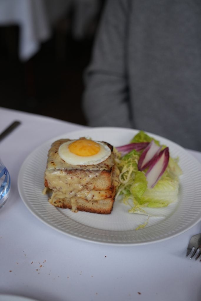 Fried egg-topped sandwich and salad at Atelier 33