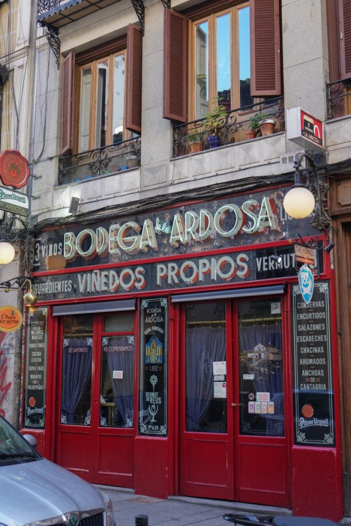 Red storefront and painted signs at Bodega de la Ardosa