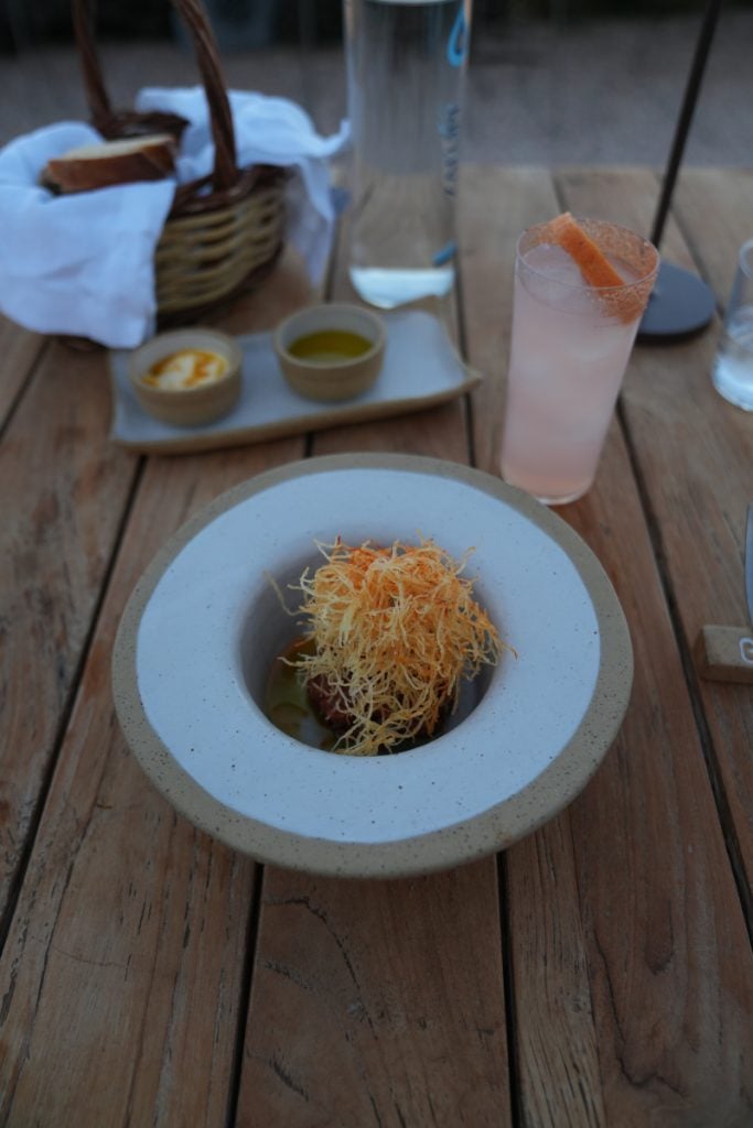 Crispy-topped dish with a pink drink at Bostani