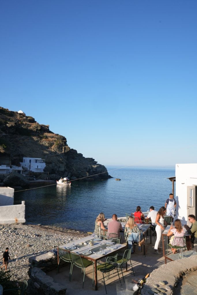 Diners on Cantina's terrace beside a rocky cove