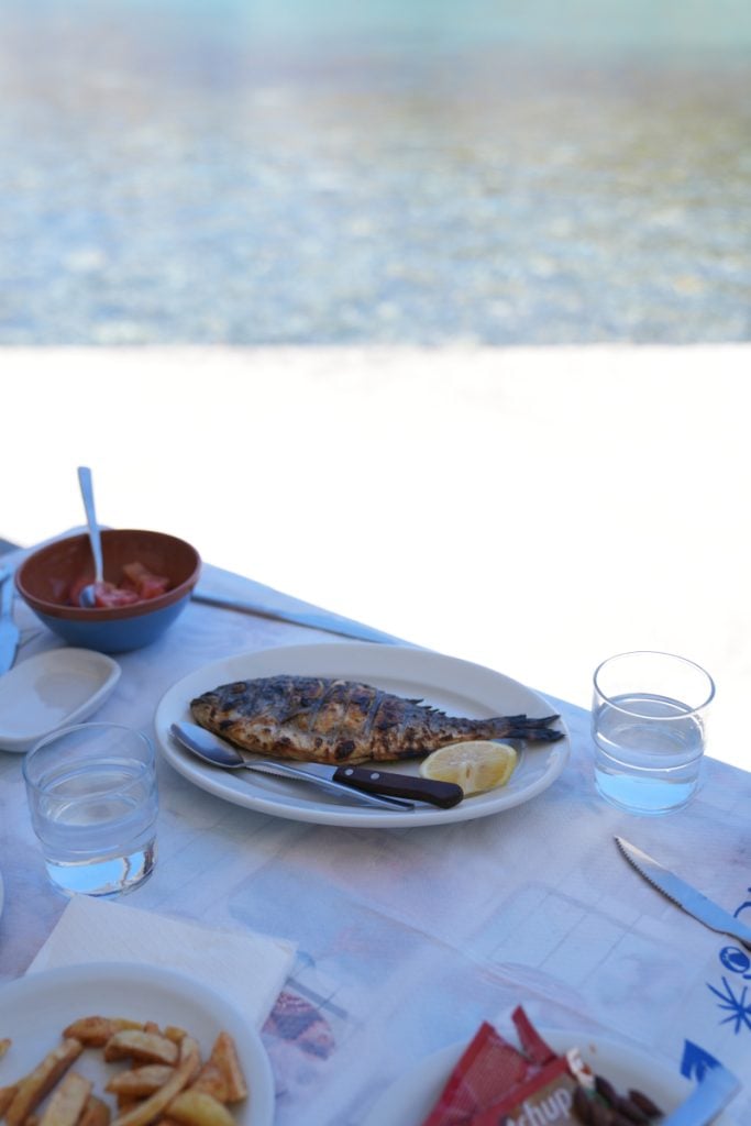 Whole grilled fish with lemon at a seaside table
