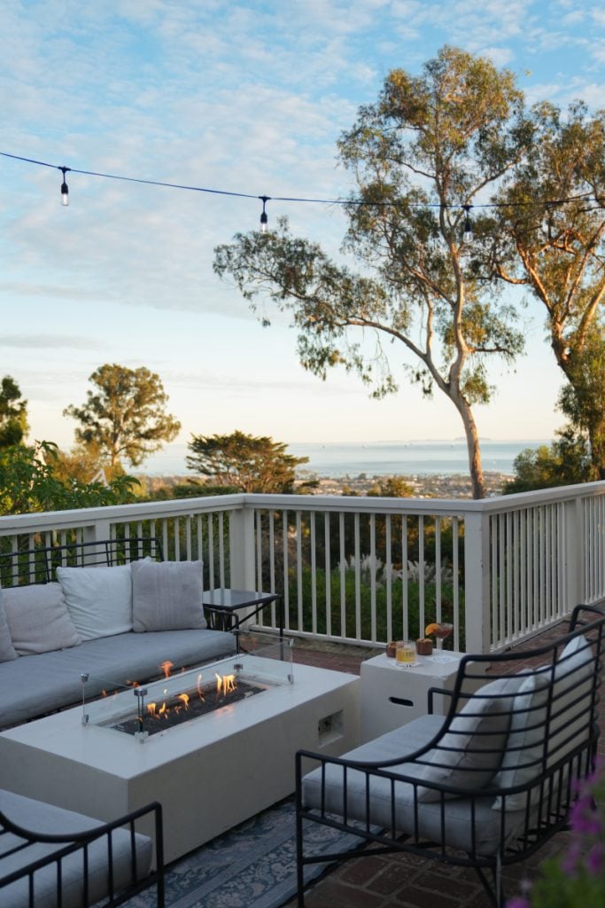 Outdoor lounge seating around a fire table with an ocean view at El Encanto