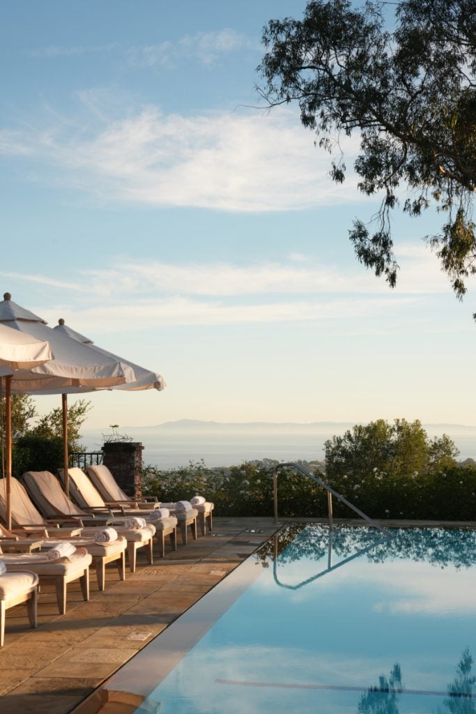 Poolside lounge chairs and umbrellas overlooking the ocean at El Encanto