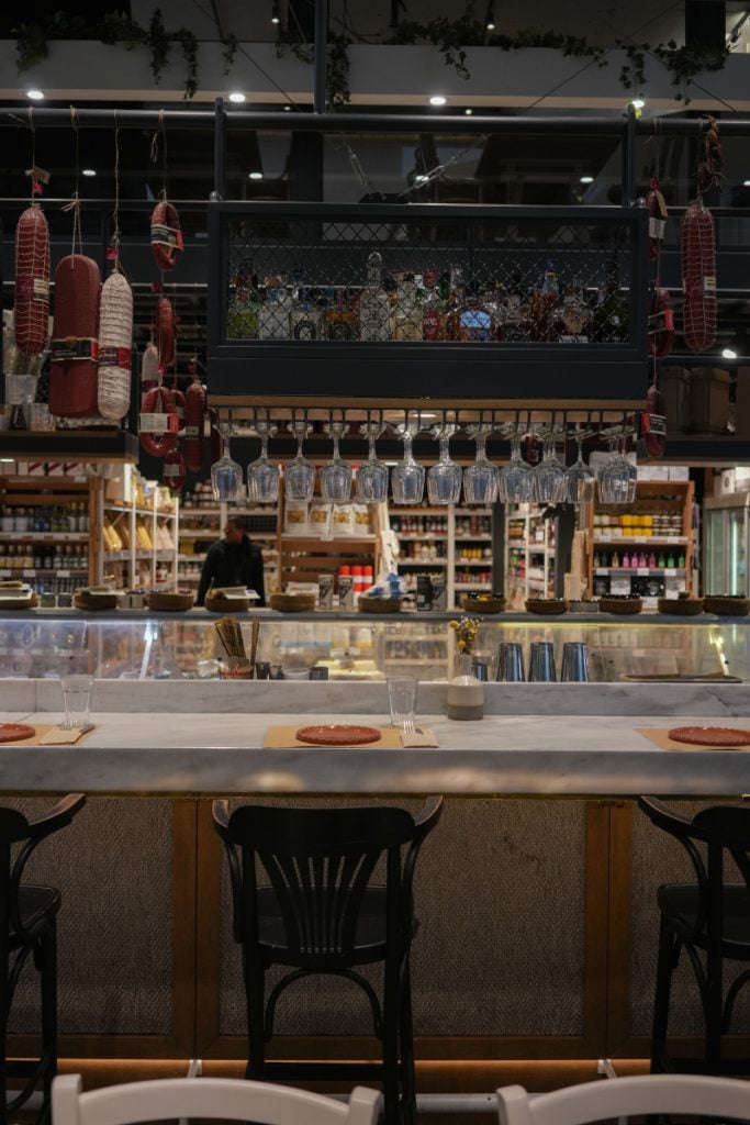 ERGON House dining counter beneath hanging glasses and cured meats