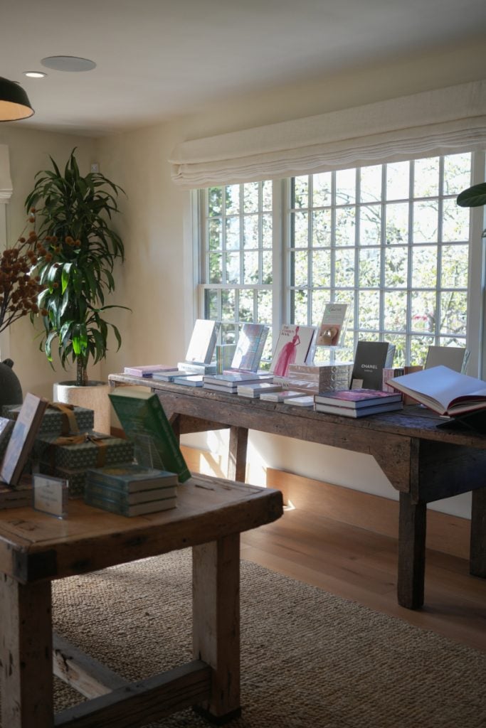 Books arranged on wooden display tables beside a sunny window at Godmothers
