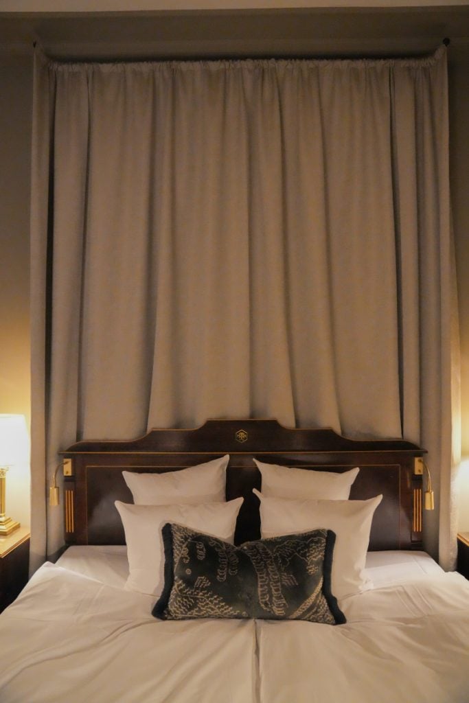 Hotel Royal bed framed by floor-to-ceiling gray curtains