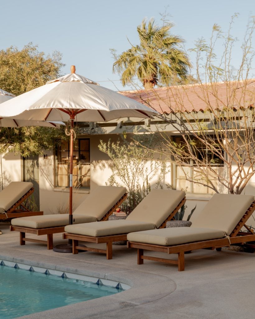 Poolside loungers and a cream umbrella at Hotel Wren