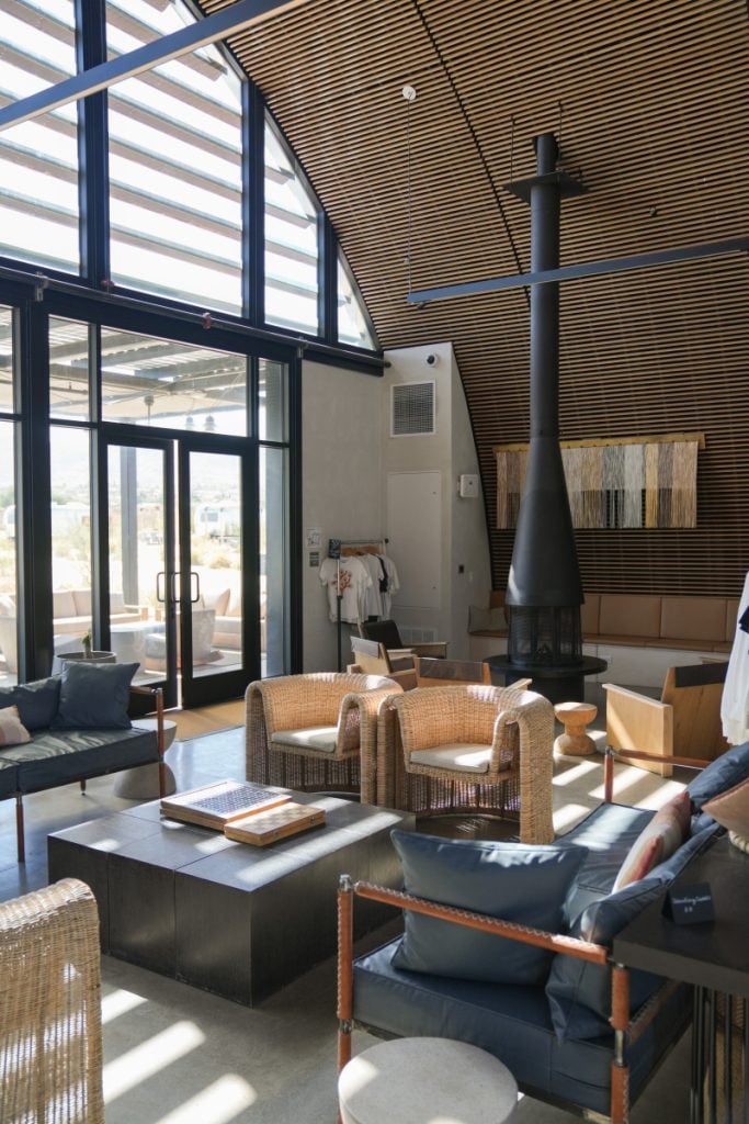 AutoCamp Joshua Tree lounge with woven chairs, a tall fireplace and large windows