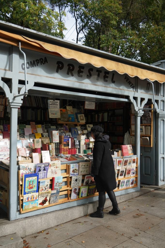 Person browsing books at the outdoor Librería Prestel stall