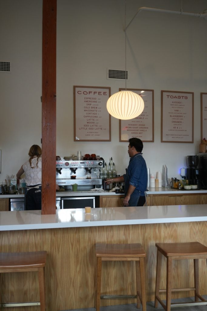 Baristas at the espresso counter beneath framed menus inside Little King Coffee