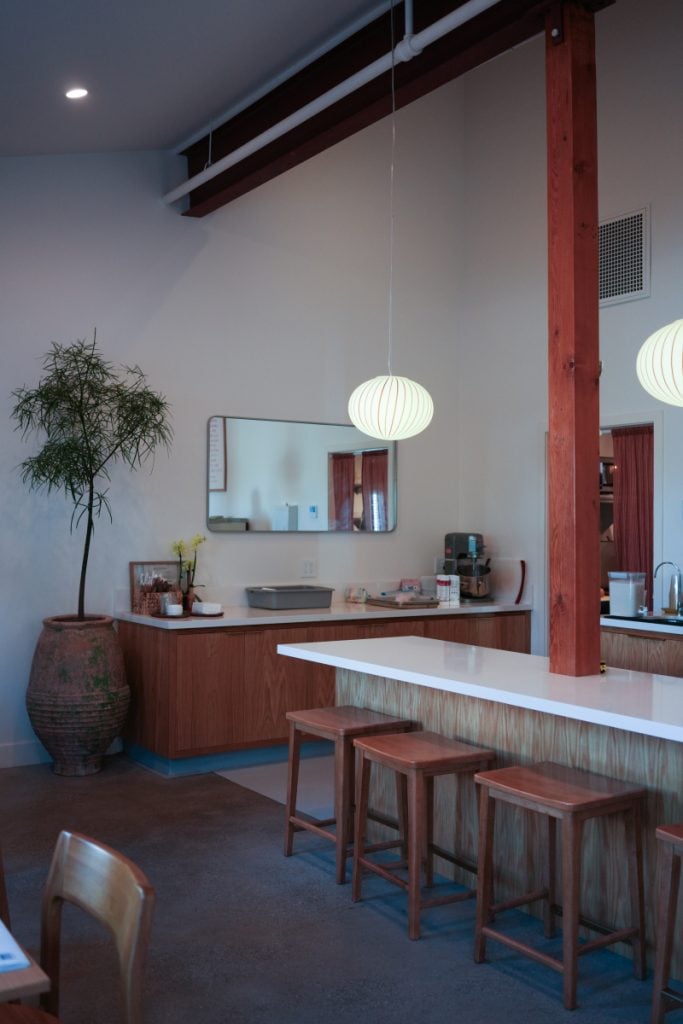 Wooden stools and pendant lights at the counter inside Little King Coffee