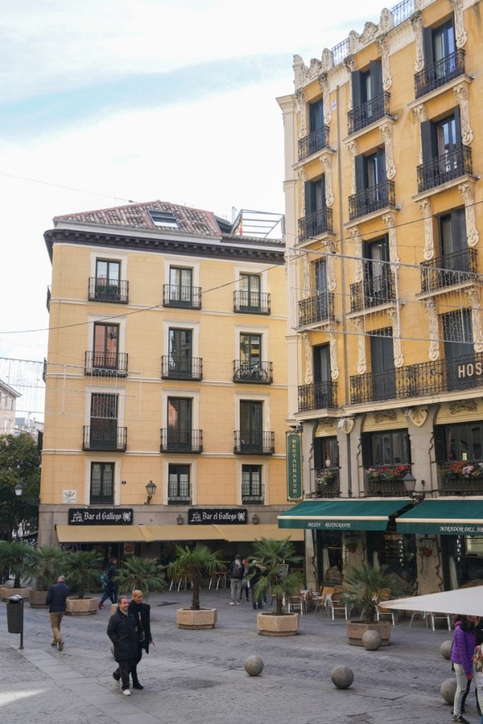 Yellow buildings with balconies above a Madrid square
