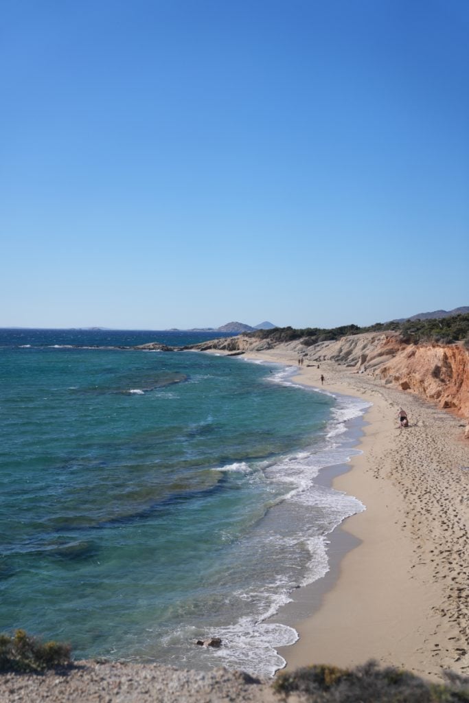 Sandy beach below rugged coastal cliffs in Naxos