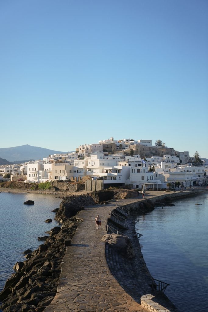 Stone causeway beside white waterfront buildings in Naxos