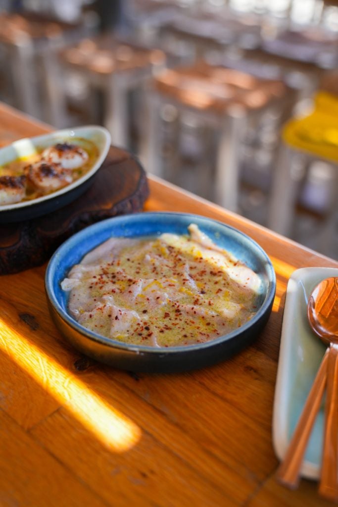 Fish carpaccio served in a blue bowl at Omega3