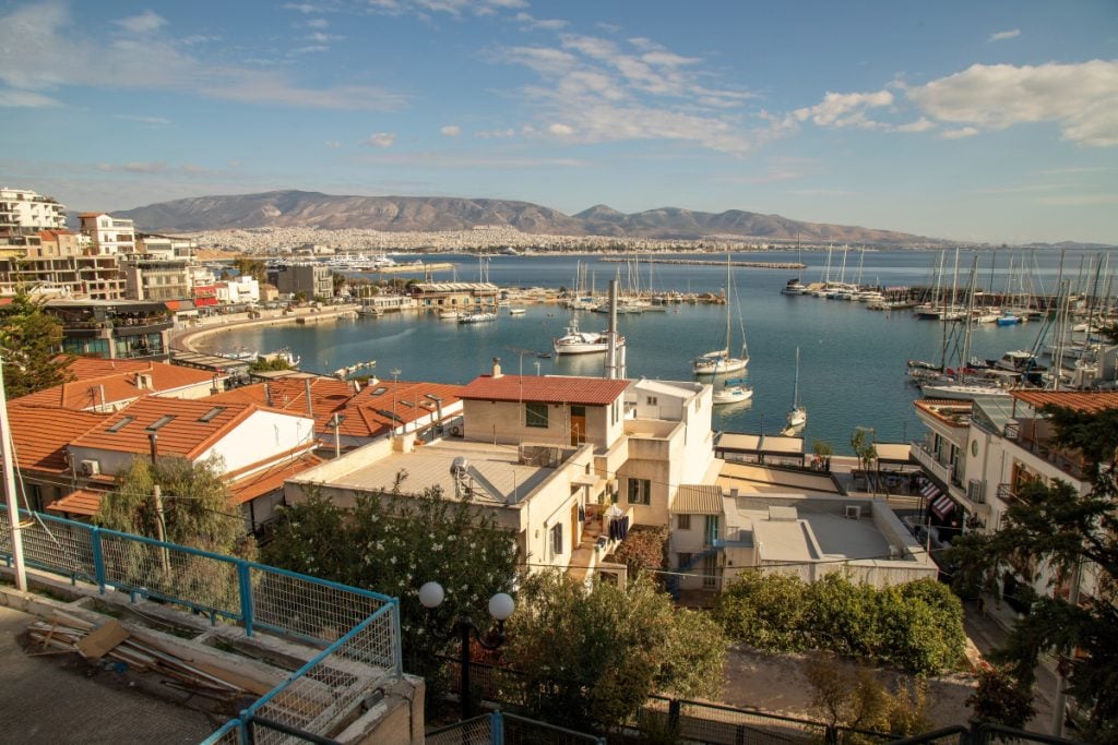 Piraeus marina with sailboats, waterfront buildings, and mountains