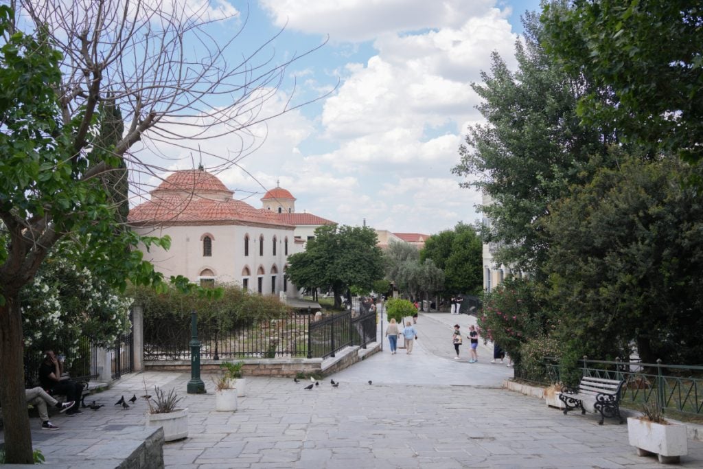 Tree-lined pedestrian walkway beside a church in Plaka