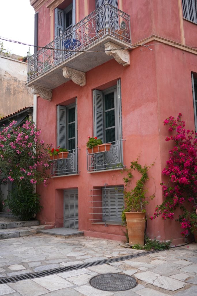 Coral building with iron balconies and bougainvillea in Plaka