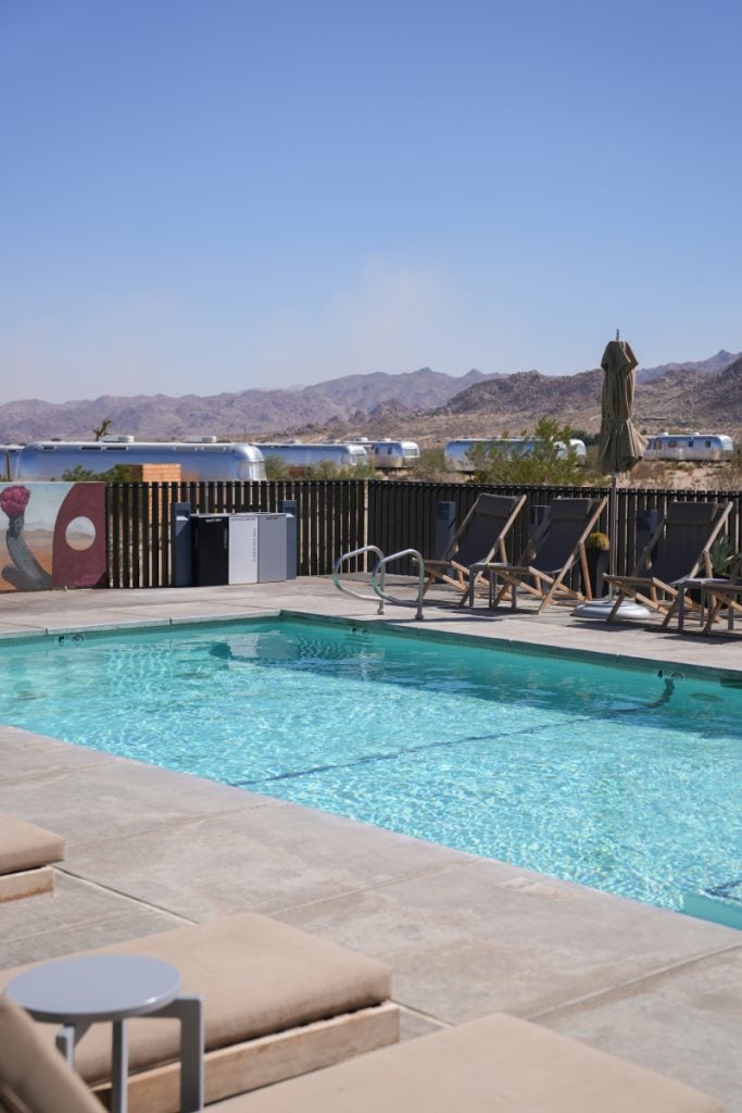 Outdoor pool and loungers with Airstream trailers beyond at AutoCamp Joshua Tree