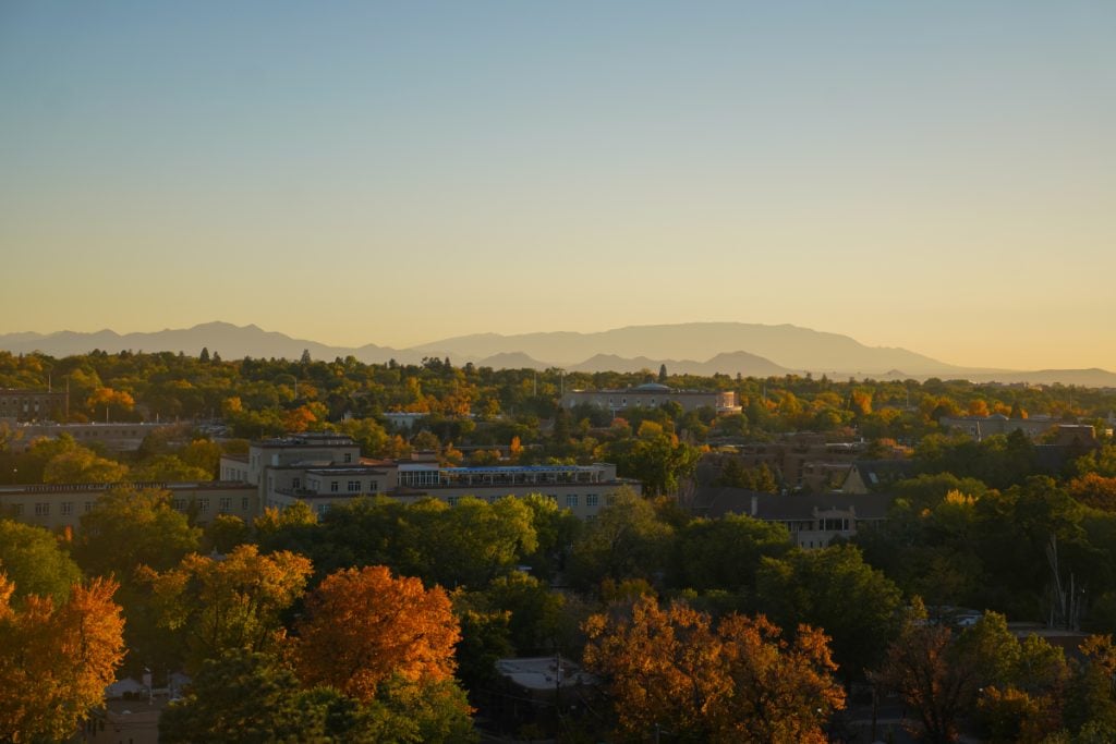 Santa Fe rooftops and autumn trees beneath distant mountains
