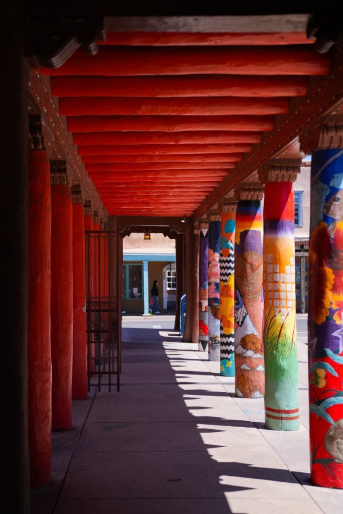 Colorfully painted columns along a shaded walkway
