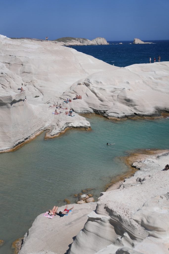 Swimmers among white volcanic rocks at Sarakiniko Beach