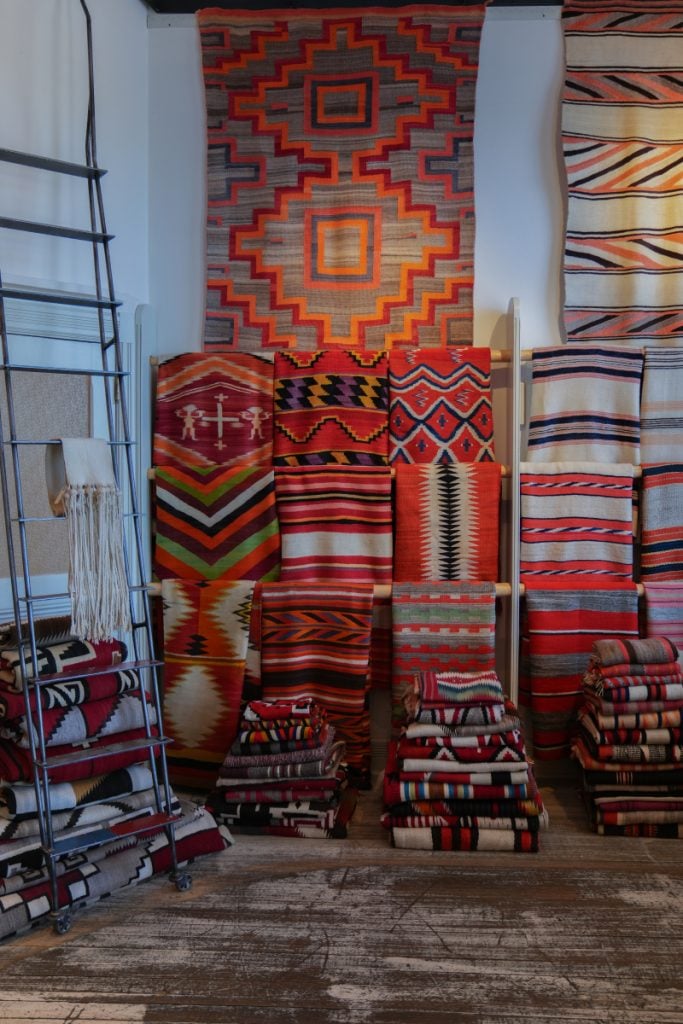 Colorful patterned rugs stacked and hung in a shop