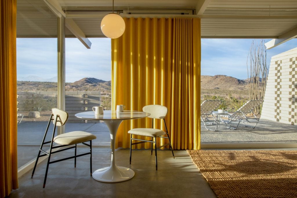 Dining nook with yellow curtains and desert views at The Bungalows at Retreat by Homestead Modern
