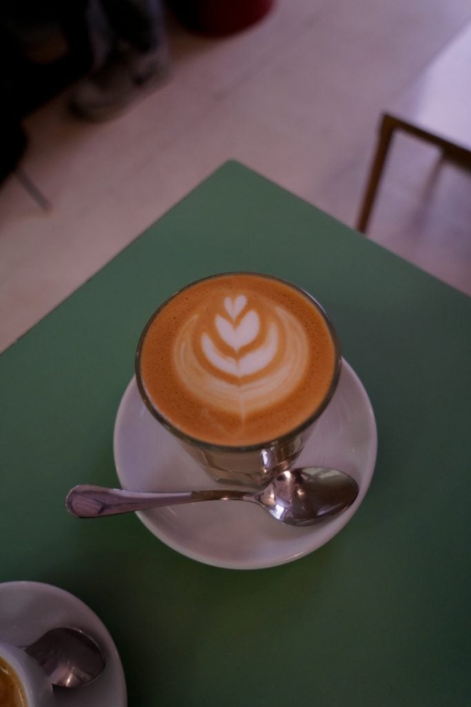 Coffee with latte art on a green table at Toma